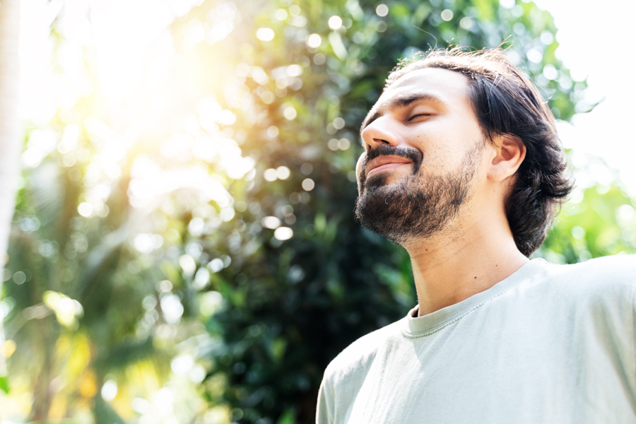 man smiling with his eyes closed and face towards the sun