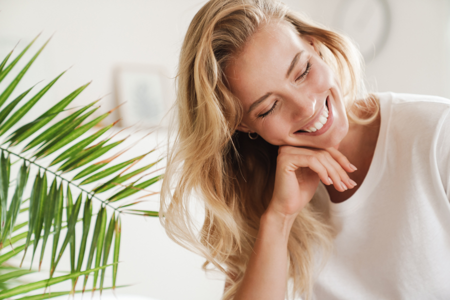 blonde woman smiling with her head resting on her hand