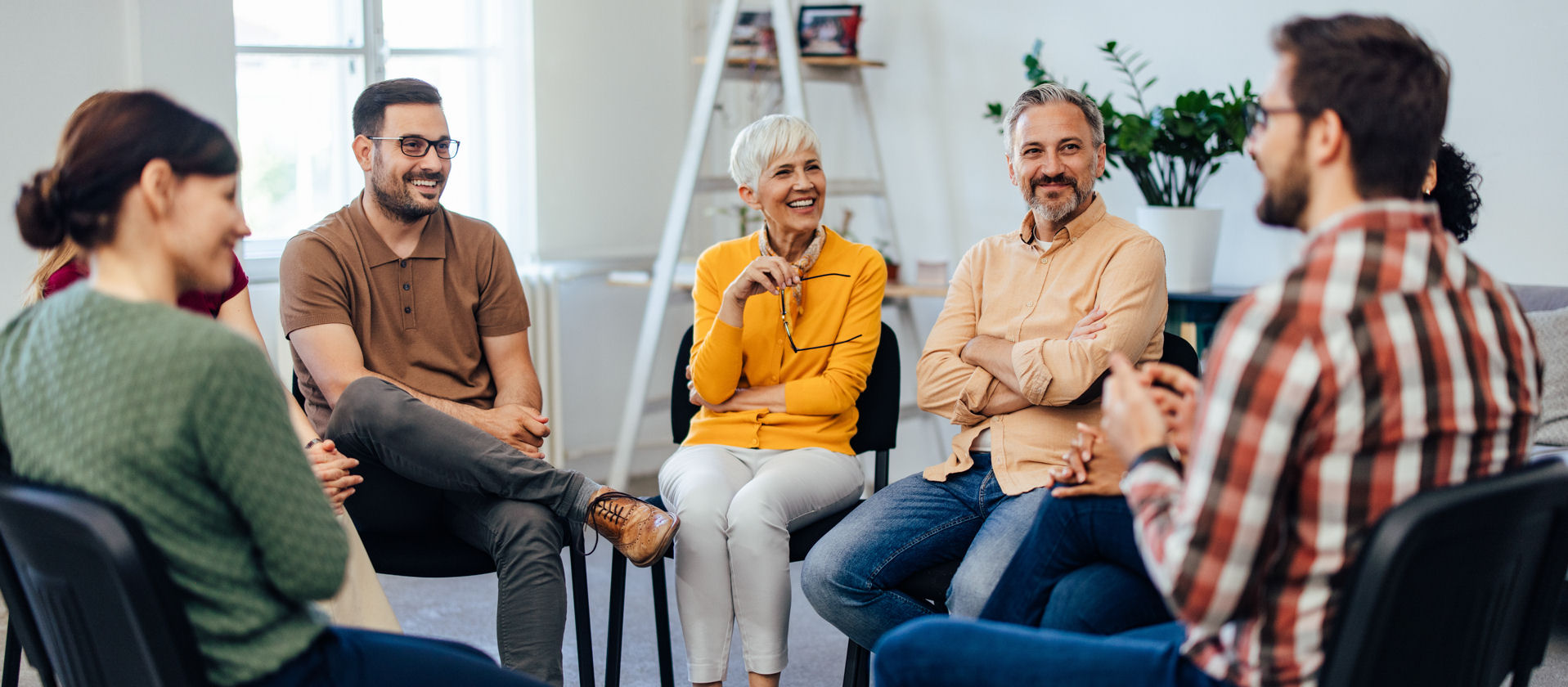 diverse group having a discussion while sitting in chairs during group therapy session