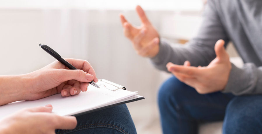 close-up on counselor taking notes during therapy session