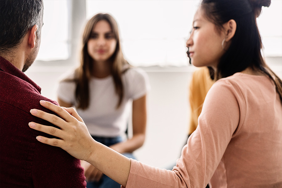 woman comforting group member in addiction therapy